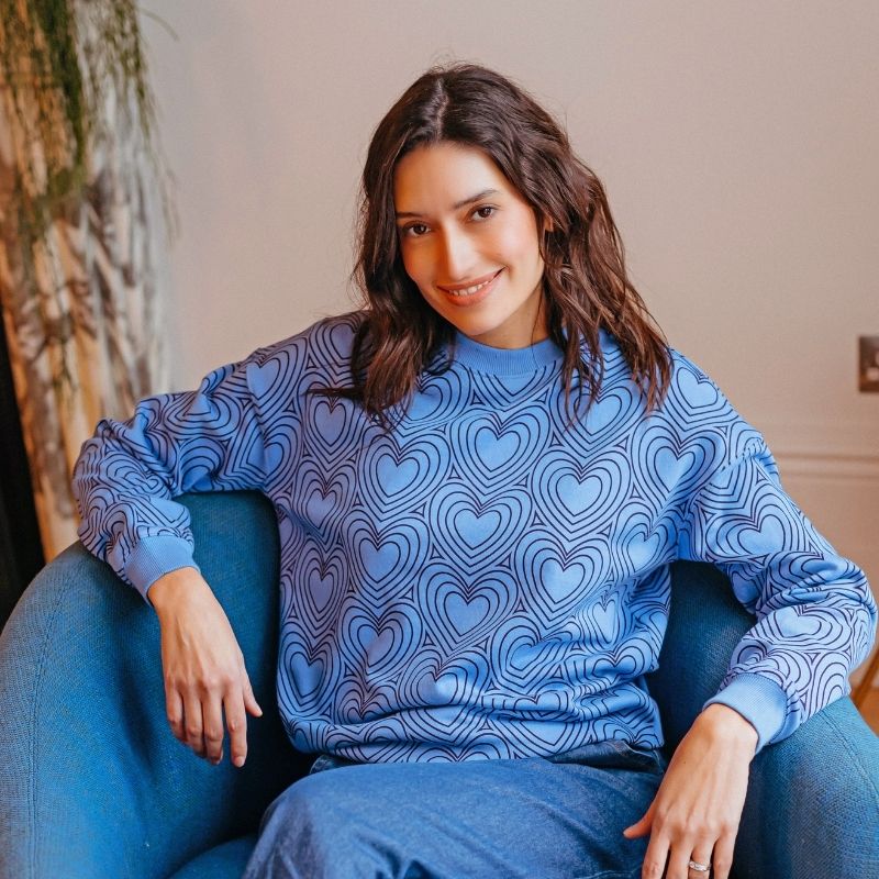 a woman wearing a blue sweatshirt with hearts on 