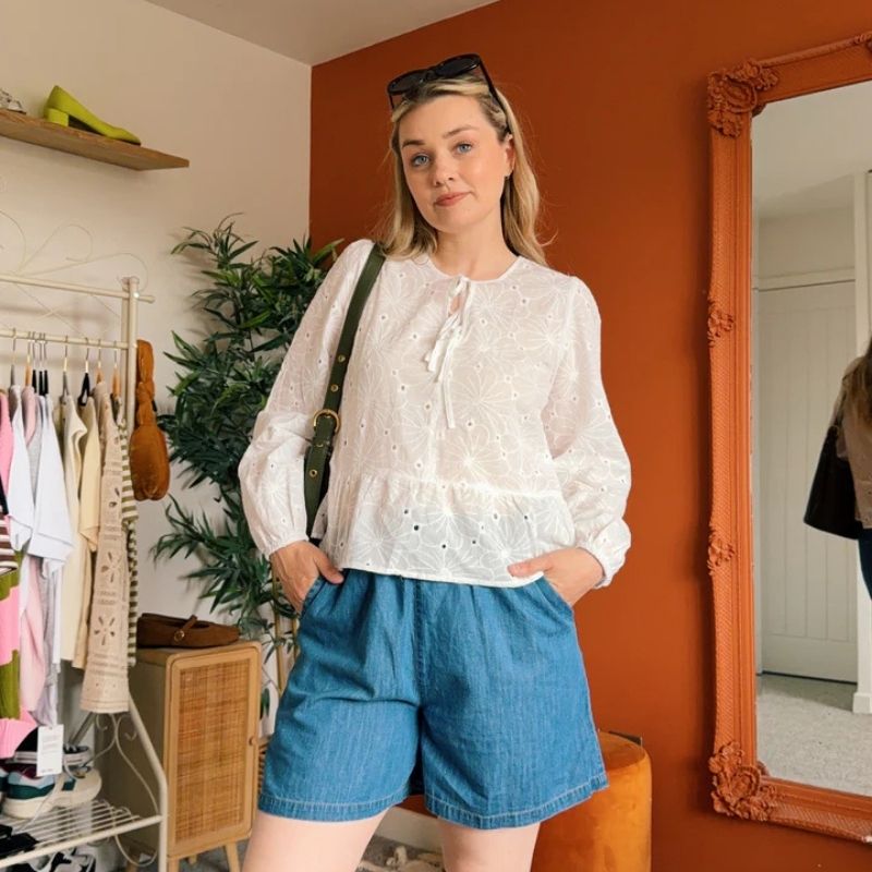 a woman wearing a white blouse and shorts 