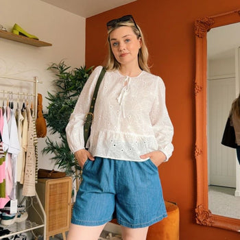 a woman wearing a white blouse and shorts 