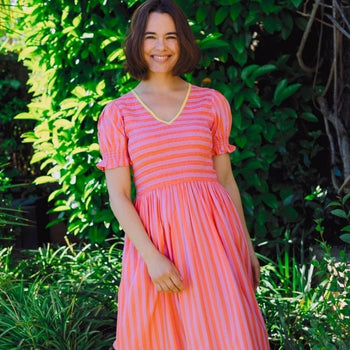 a woman wearing a striped coral dress