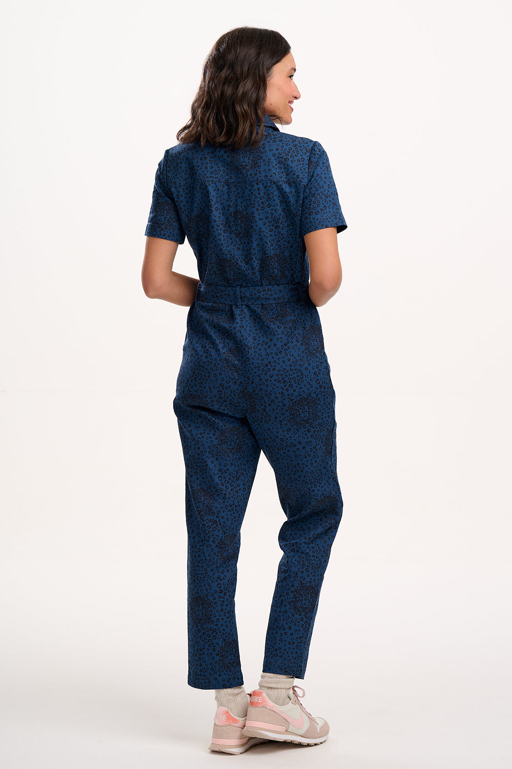 Sugarhill Brighton model wearing a blue patterned jumpsuit on a white background