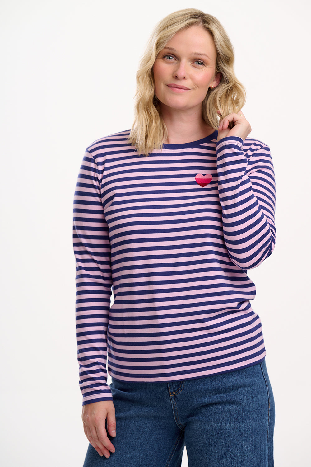 Sugarhill Brighton model wearing a striped long-sleeve shirt with a heart detail on a white background