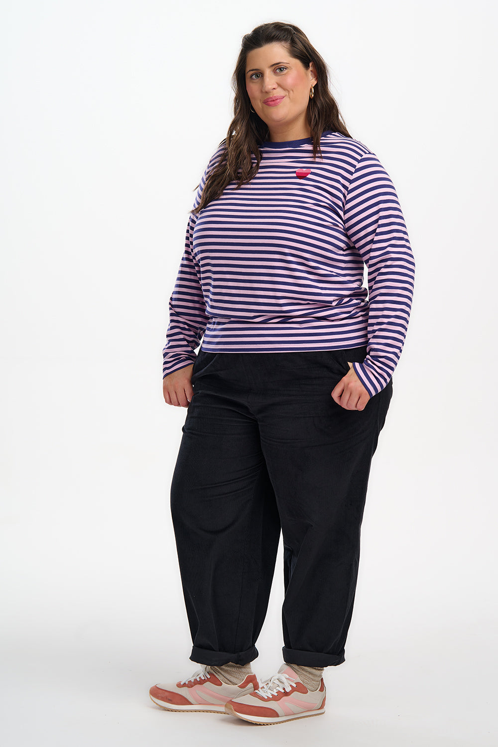 Woman wearing a striped shirt and black pants on a white background