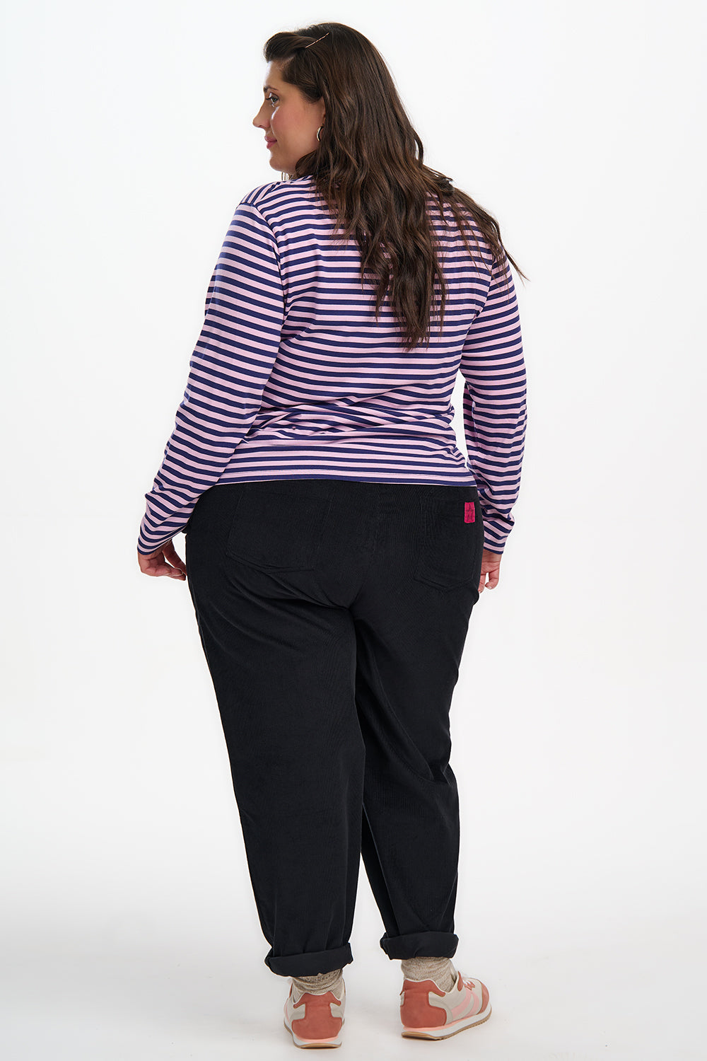 Person wearing a striped shirt and black pants on a white background