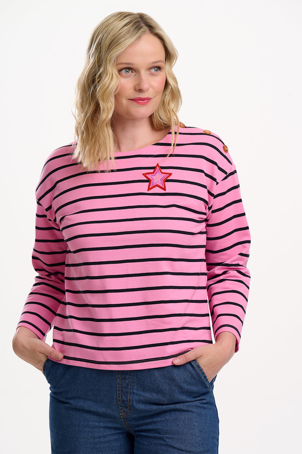 Sugarhill brighton model wearing a pink and black striped sweater with a star accessory on a white background