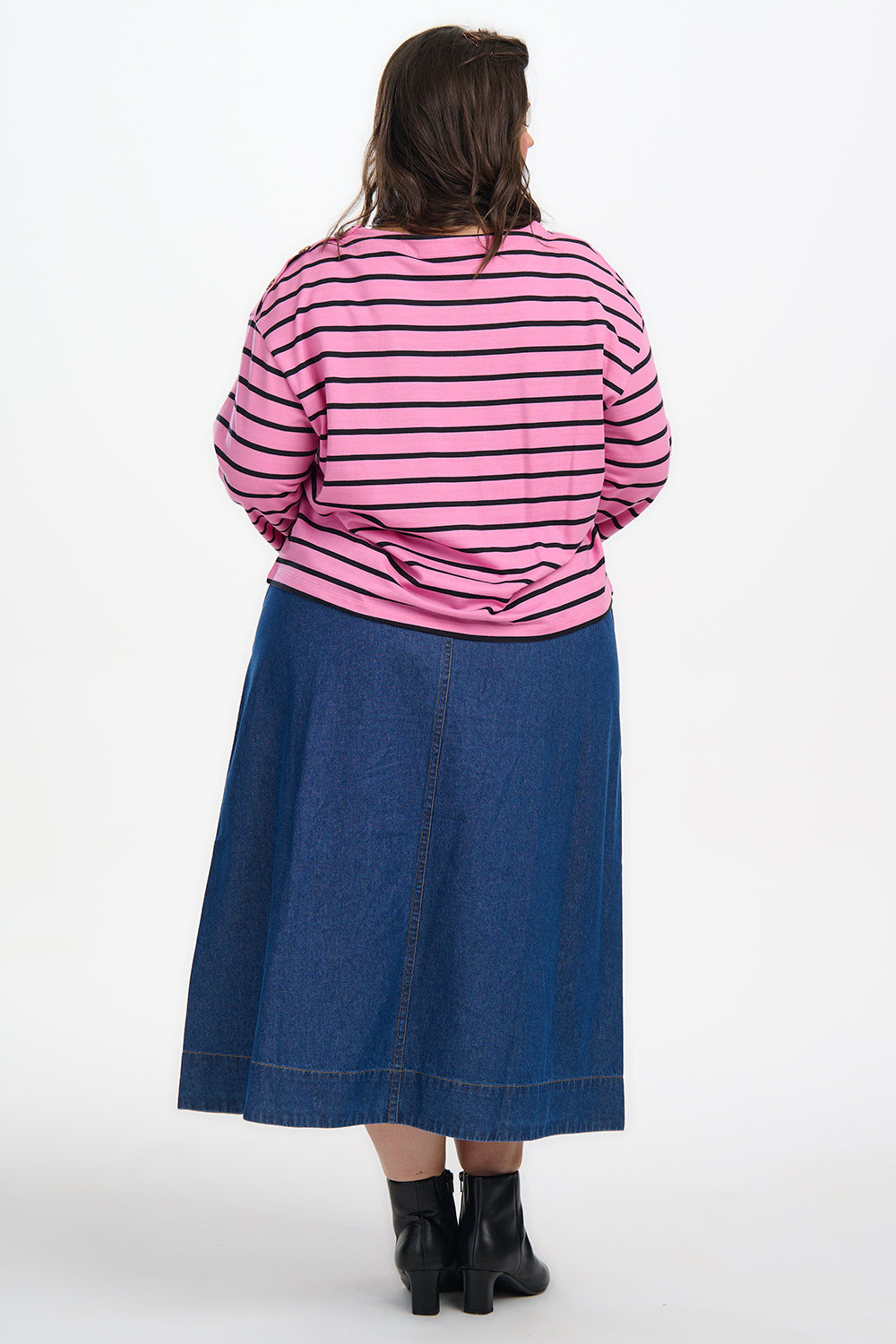 Person wearing a pink striped shirt and blue denim skirt on a white background
