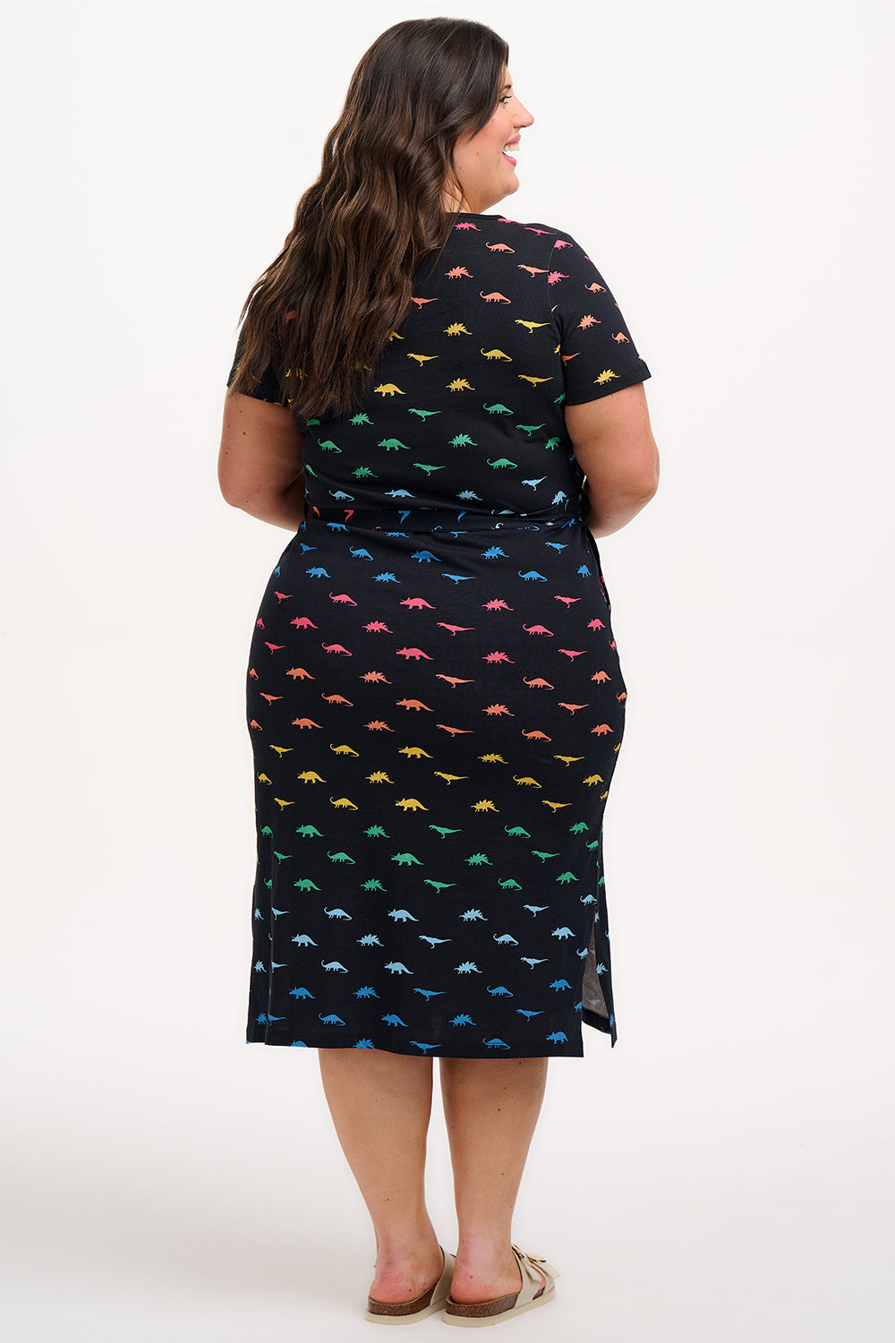 Woman wearing a black dress with colorful dinosaur pattern on a white background