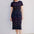 Woman wearing a black dress with colorful fish pattern on a white background