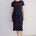 Woman wearing a black dress with colorful fish pattern on a white background