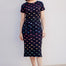 Woman wearing a black dress with colorful fish pattern on a white background