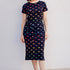 Woman wearing a black dress with colorful fish pattern on a white background