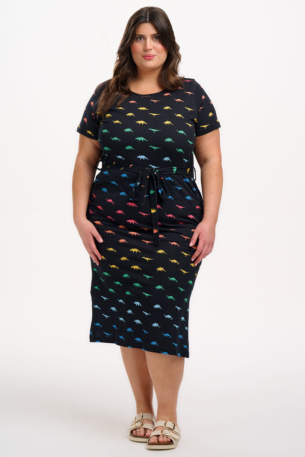 Woman wearing a black dress with colorful dinosaur pattern on a white background