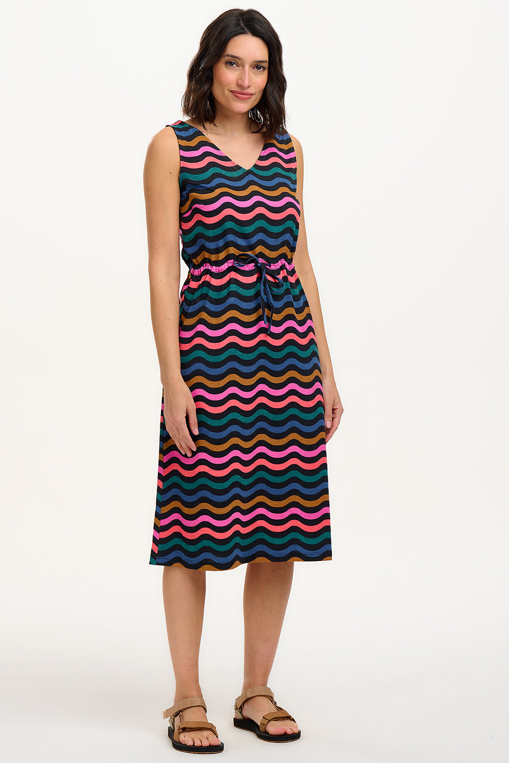A model wearing a sleeveless midi dress with a wavy chevron stripe pattern in black, teal, navy, tan, pink, and coral colors.