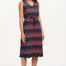 A model wearing a sleeveless midi dress with a wavy chevron stripe pattern in black, teal, navy, tan, pink, and coral colors.