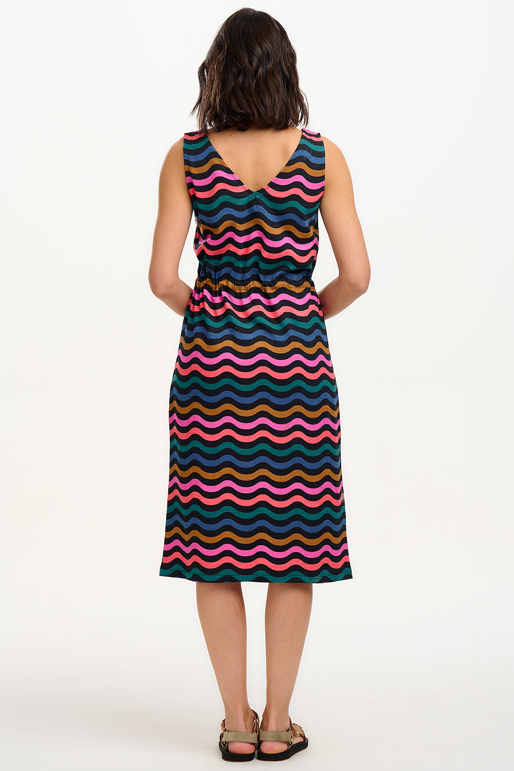 A model wearing a sleeveless midi dress with a wavy chevron stripe pattern in black, teal, navy, tan, pink, and coral colors.