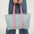 Person holding a striped tote bag with pink straps against a white background