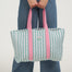 Person holding a striped tote bag with pink straps against a white background