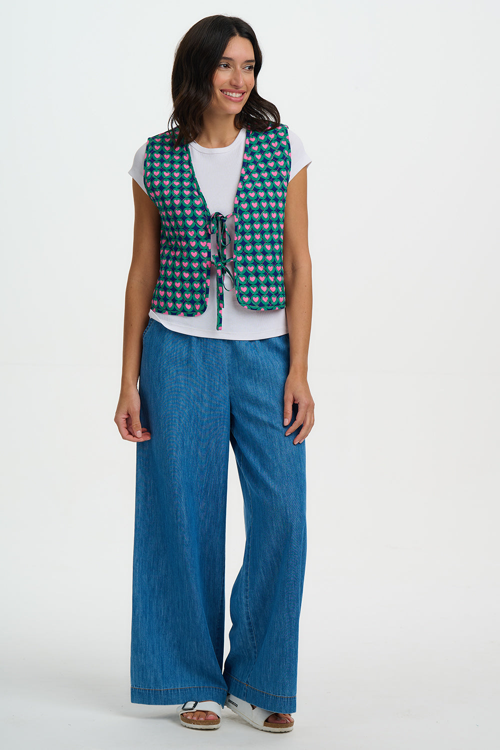 Woman wearing a green checkered vest and blue pants on a white background
