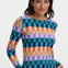 Woman wearing a colorful checkered top with a plain background