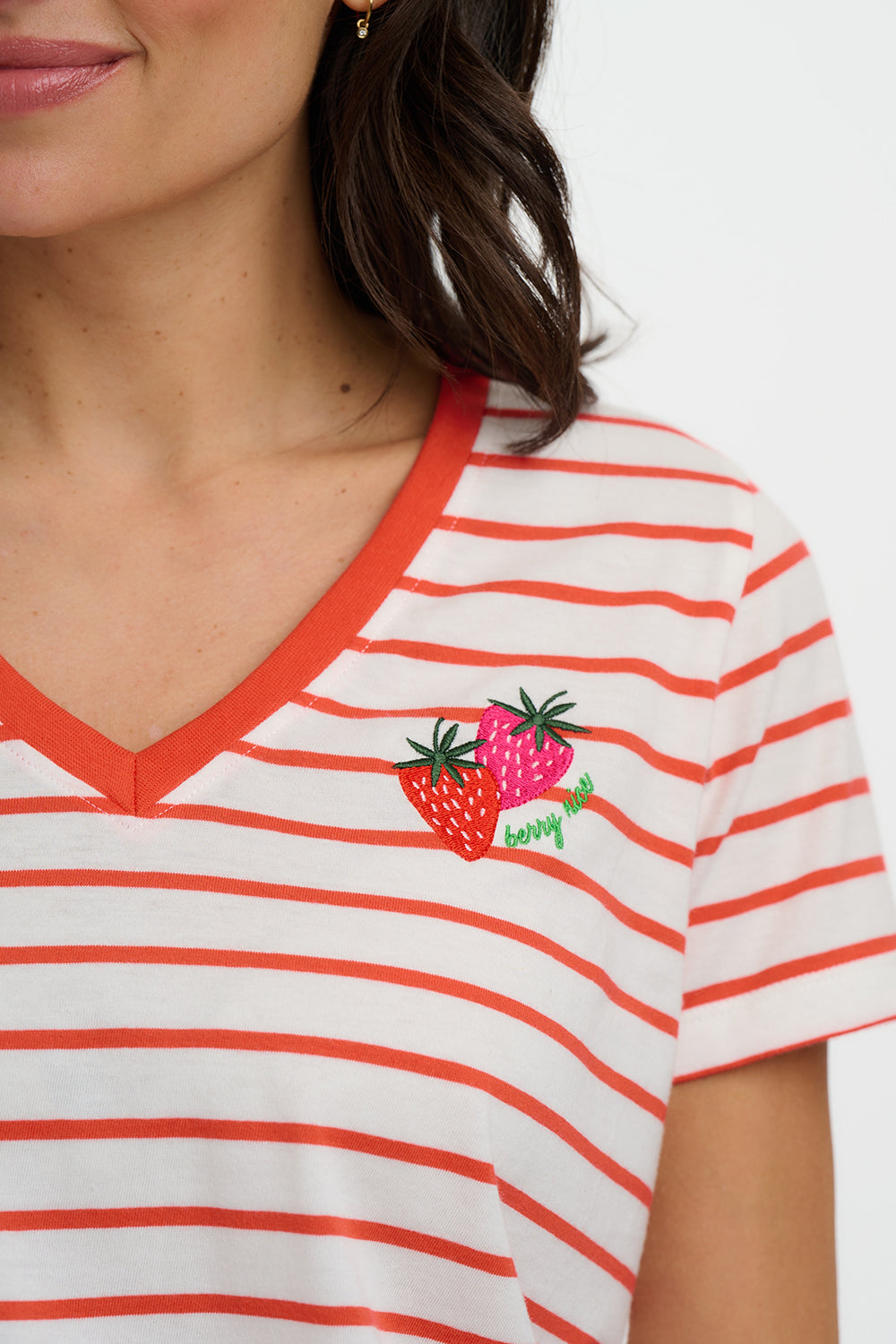 Close-up of a person wearing a red and white striped shirt with a strawberry design.