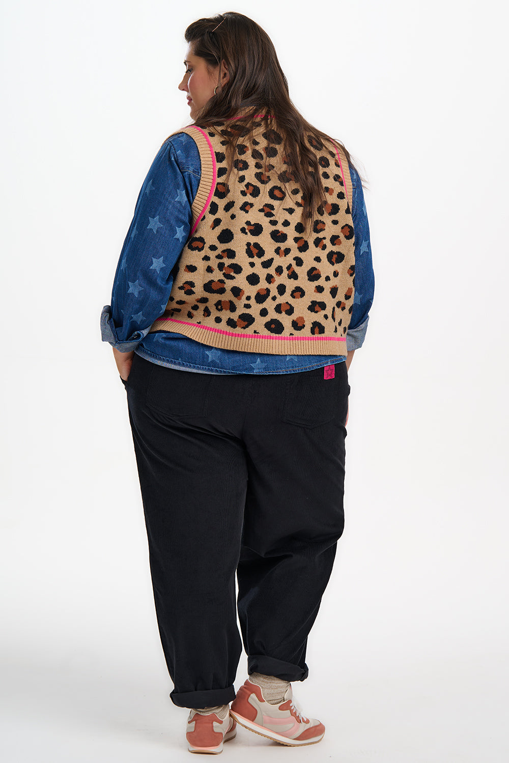 Person wearing a blue denim jacket with a leopard print back panel on a white background