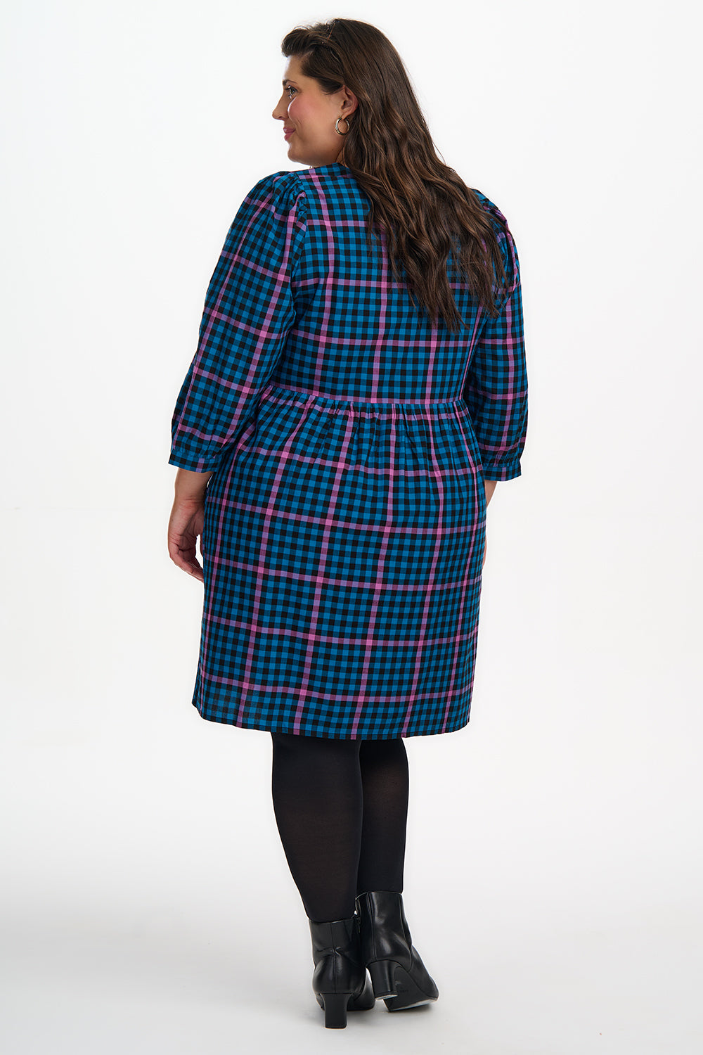 Woman wearing a blue and pink plaid coat on a white background