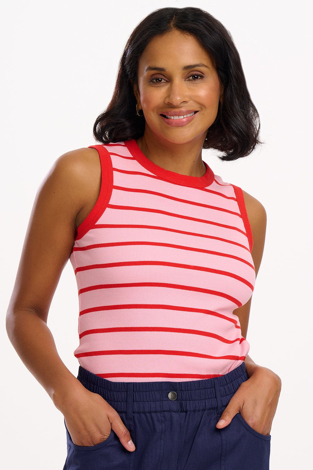A woman wearing a sleeveless fitted pink vest with red stripes, round neckline, and contrast bands around the arm holes.