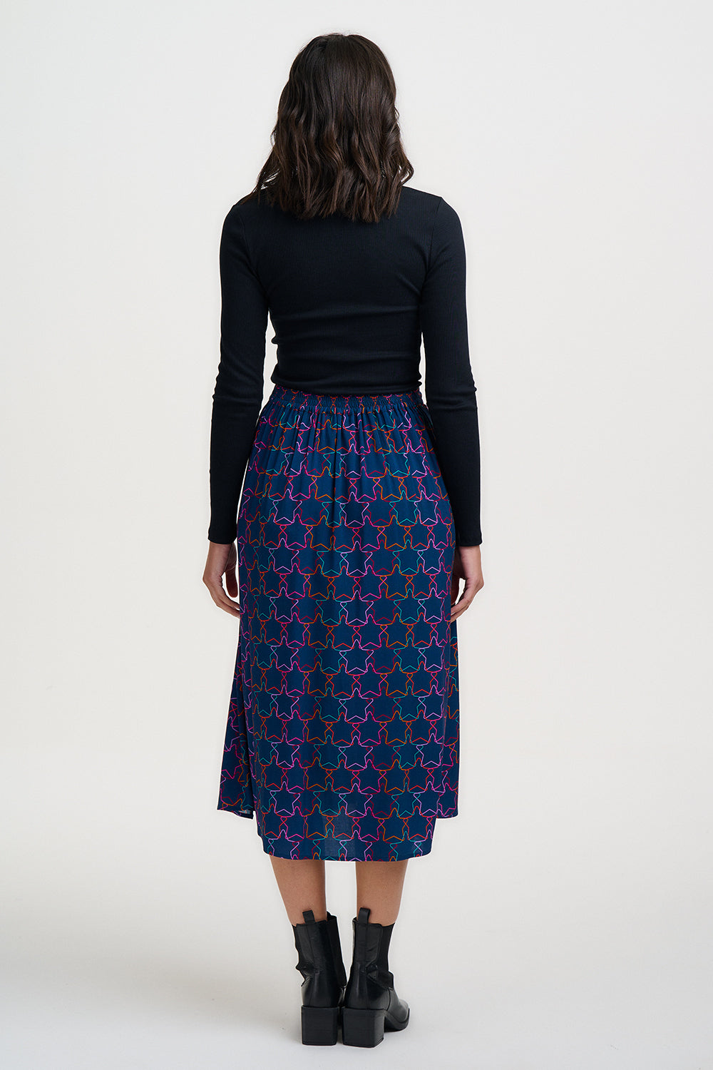 Person wearing a black top and patterned skirt on a white background