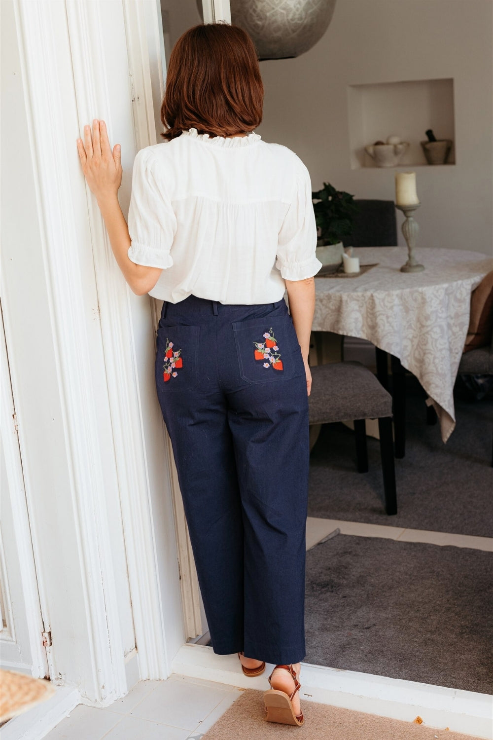 Woman wearing a white blouse with floral embroidery and blue pants