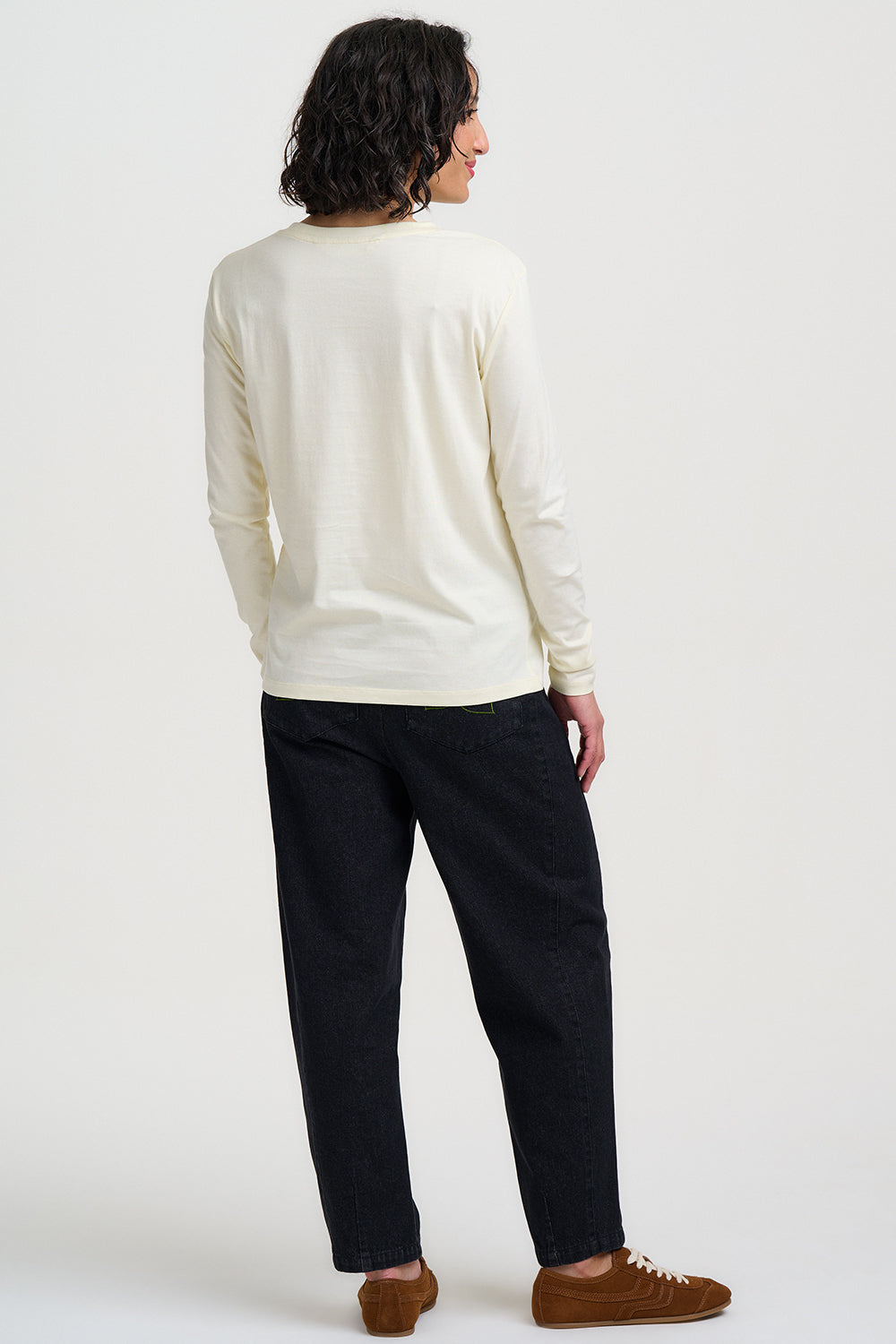 Person wearing a cream sweater and dark pants on a white background