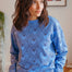 Woman wearing a blue sweater with heart pattern indoors