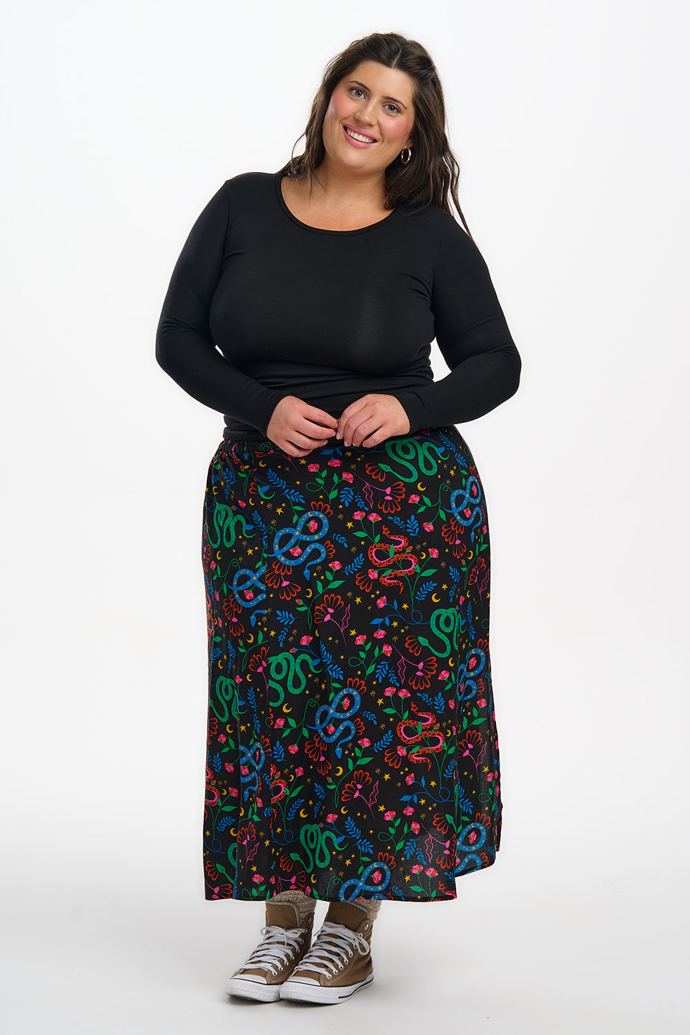 Woman wearing a black top and colorful patterned skirt on a white background
