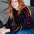 Woman wearing a colorful striped sweater sitting on a couch.