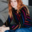 Woman wearing a colorful striped sweater sitting on a couch.