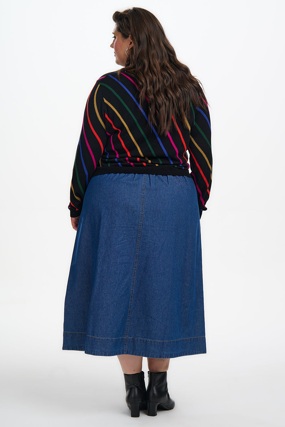 Person wearing a colorful striped sweater and blue skirt on a white background
