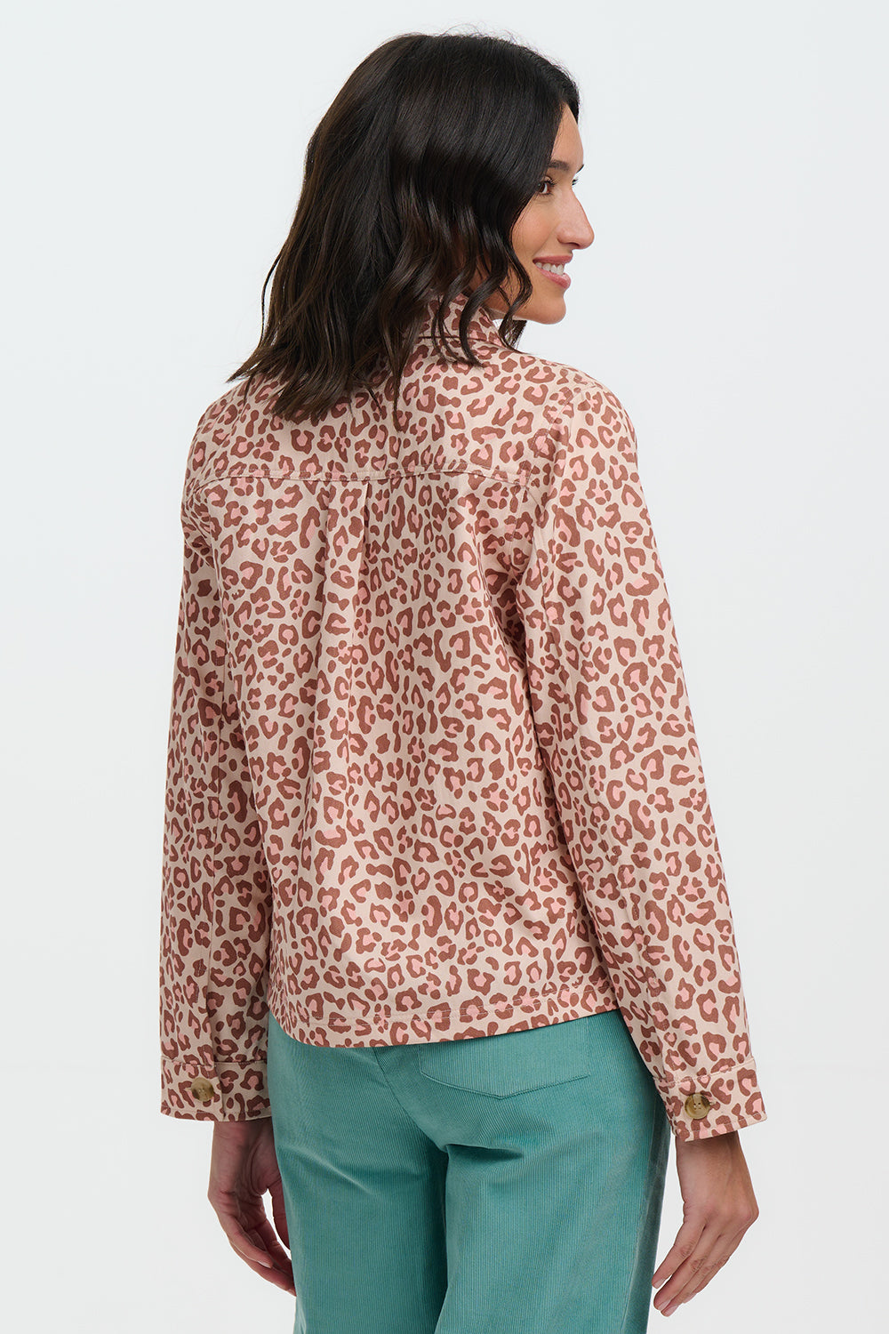 Woman wearing a leopard print blouse and green pants on a white background