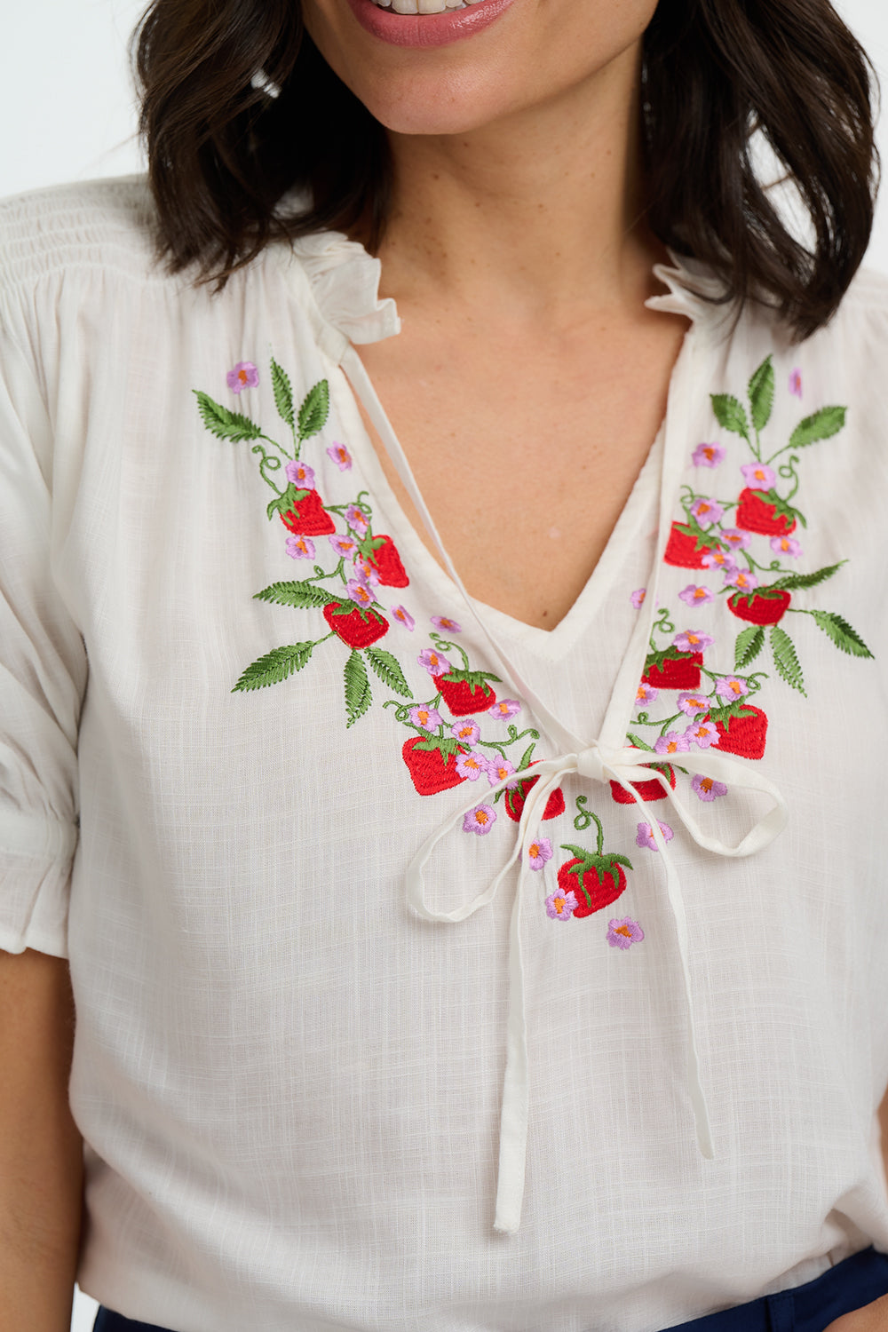 White blouse with floral embroidery on a white background