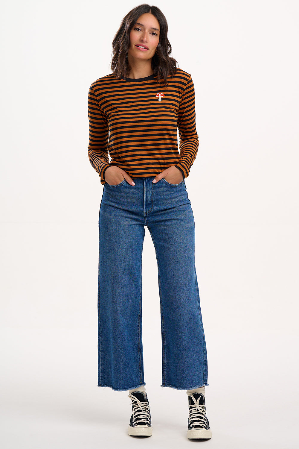 Sugarhill Brighton - Model wearing a striped long-sleeve shirt and blue jeans on a white background