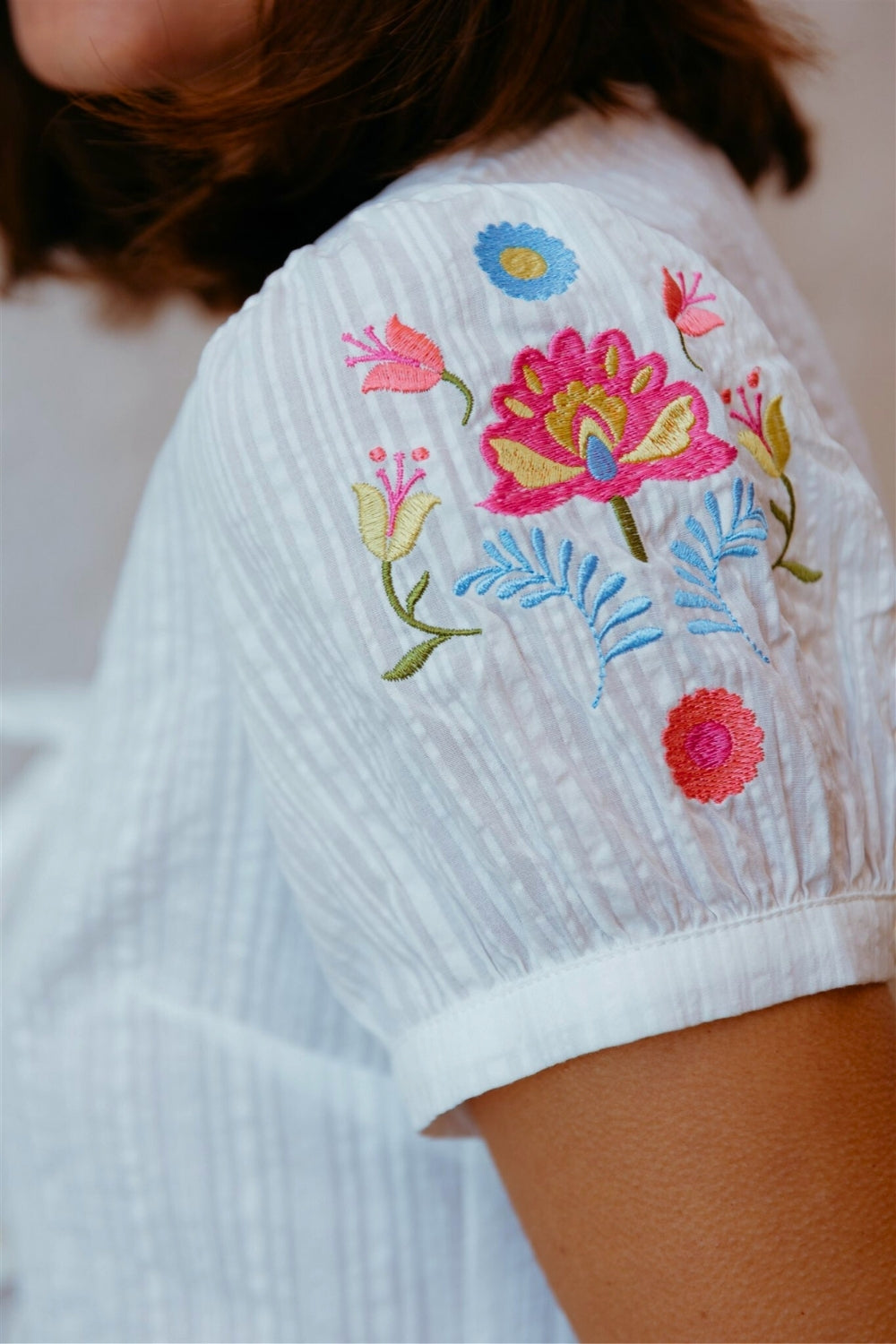 White garment with colorful floral embroidery on a blurred background