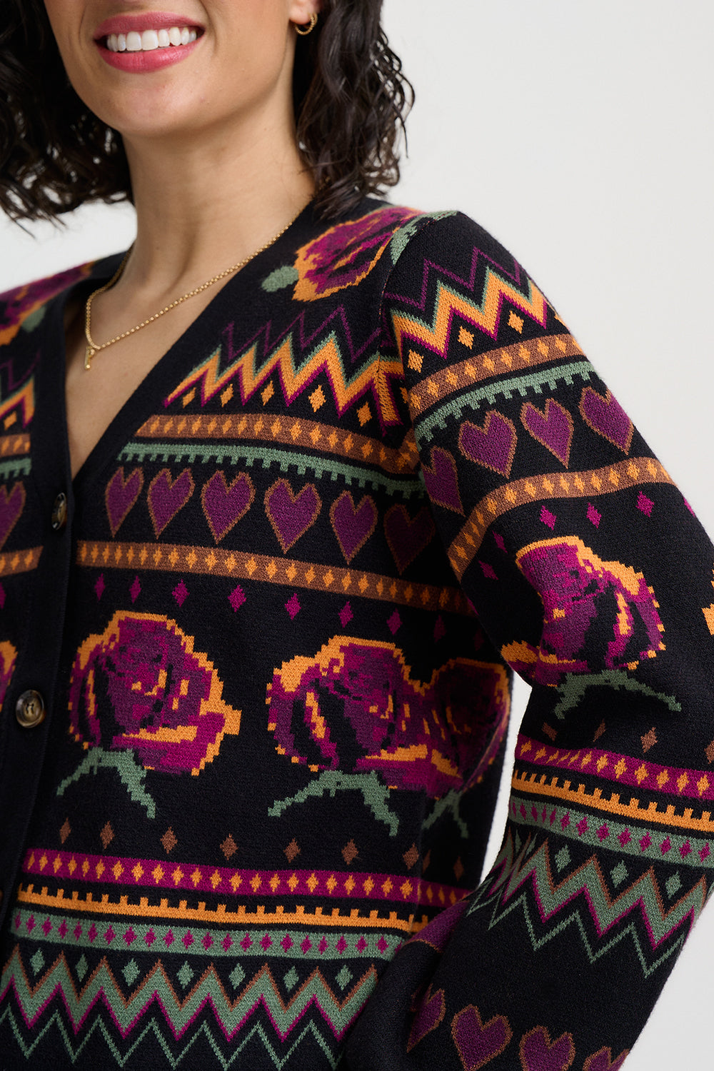 Person wearing a black sweater with colorful geometric and floral patterns on a white background