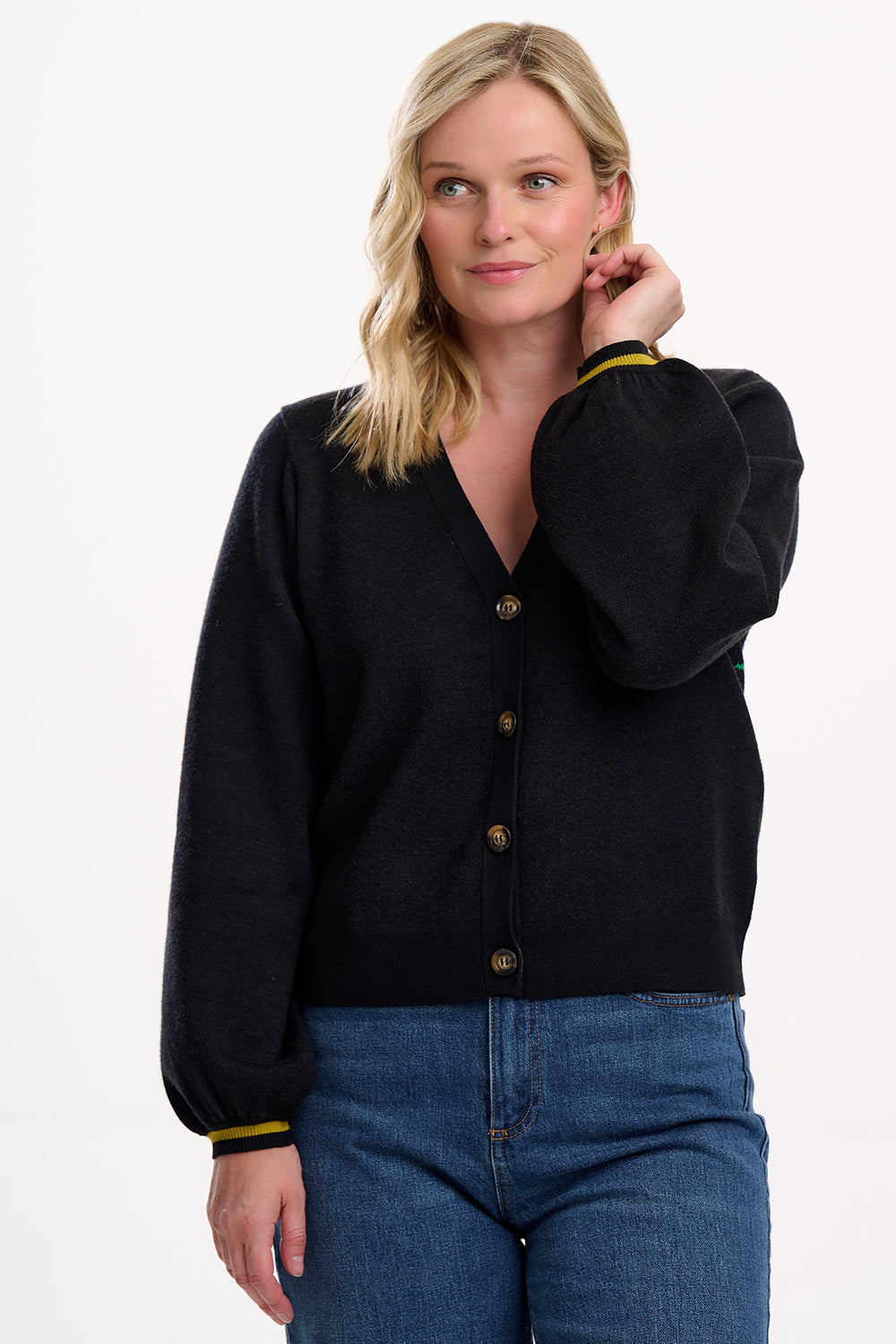 Woman wearing a black cardigan with yellow trim on a white background