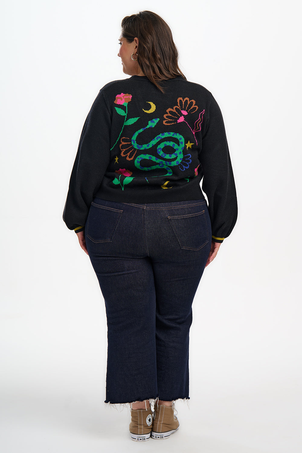 Person wearing a black sweatshirt with colorful snake design on the back, standing against a white background.