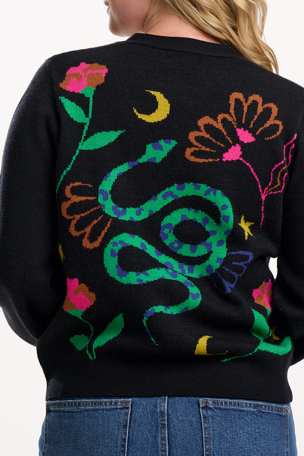 Black sweater with colorful snake and floral design on the back, worn by a person.