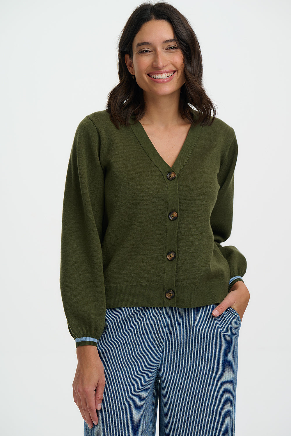 Woman wearing a green cardigan and blue pants on a white background