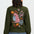 Person wearing a green sweater with a colorful animal and floral design on the back against a white background