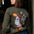 Person wearing a green sweatshirt with colorful designs on the back, standing indoors.