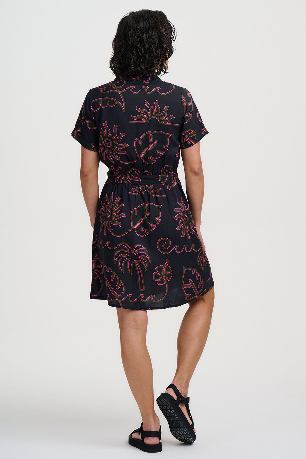 Person wearing a black dress with red floral patterns on a white background