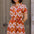 Woman wearing a patterned dress standing in front of a door.