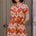 Woman wearing a patterned dress standing in front of a door.