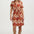 Woman wearing a patterned dress with a plain background